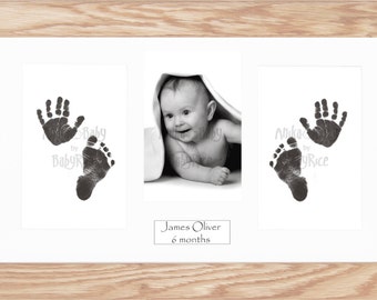 May include: A black and white photo of a baby with their hand and footprint prints. The baby is under a blanket and smiling. The photo is in a white frame with a black mat. The text "James Oliver 6 months" is below the photo.