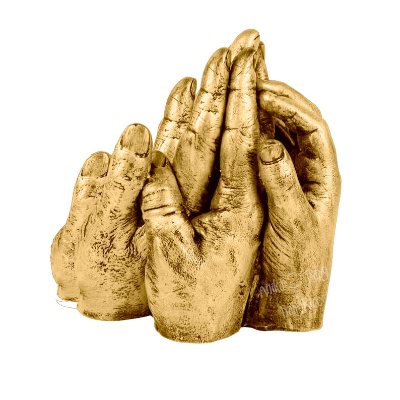 May include: A gold-toned handprint sculpture of three hands, two adult hands and one smaller child's hand, all clasped together.