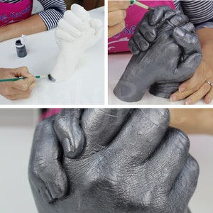 May include: A silver-colored hand cast of two hands holding each other. The cast is detailed and shows the texture of the skin.
