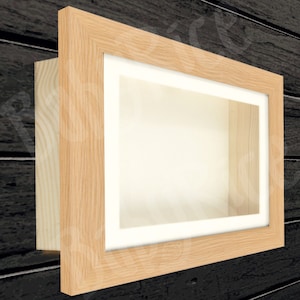May include: A light wood shadow box frame with a white mount and a clear glass front. The frame is mounted on a dark wood wall.