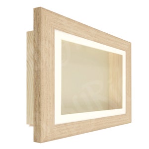 May include: A light wood shadow box frame with a white mat and a clear glass front. The frame is perfect for displaying small items, such as coins, jewelry, or other collectibles.