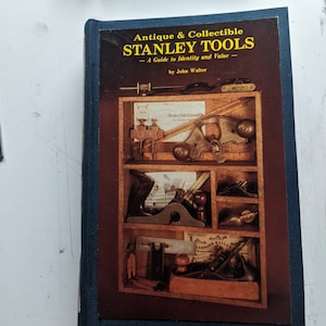 May include: A blue hardcover book titled "Antique & Collectible STANLEY TOOLS - A Guide to Identity and Value - by John Walter". The cover features a photograph of a wooden tool chest with various tools inside.