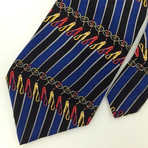May include: A blue and black striped tie with a repeating pattern of red, yellow, and black ski poles. The ski poles have a chain detail.