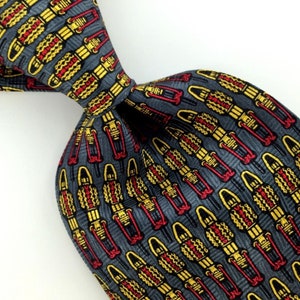 May include: A gray silk tie with a repeating pattern of yellow, red, and black stylized figures. The figures are arranged in vertical rows.