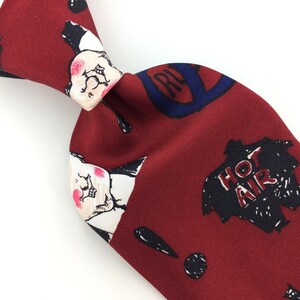 May include: A red silk tie with a whimsical pattern featuring cartoon faces, a musical note, and the words "Hot Air".