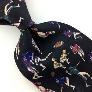 May include: Black silk tie with a repeating pattern of football players in various poses and colors. The tie features a black background with white, red, blue, green, and yellow accents.