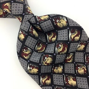 May include: A gray silk tie with a repeating pattern of a cartoon Tasmanian Devil in a black and white checkered design.