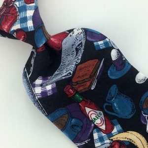 Może przedstawiać: Czarny jedwabny krawat z kolorowym nadrukiem jedzenia na śniadanie, w tym jajek, tostów, kawy i butelki sosu pikantnego. Nadruk zawiera również kratkę i gazetę.