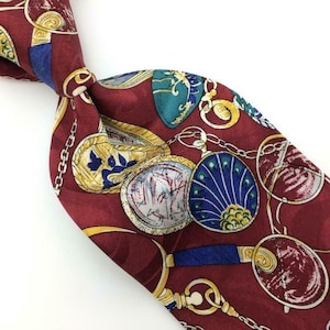 May include: A red silk tie with a pattern of antique pocket watches, compasses, and magnifying glasses. The design features gold chains, blue and green accents, and a vintage aesthetic.