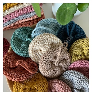 Peut inclure: Une collection d'éponges à récurer tricotées de différentes couleurs, dans des nuances de rose, vert, bleu, jaune, marron et gris. Les éponges sont disposées en cercle sur une surface en bois.