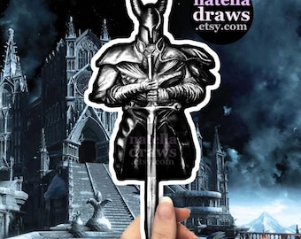 May include: A black and white sticker featuring a knight holding a sword, set against a gothic cathedral and a dark, cloudy sky. The sticker has the text "natella draws .etsy.com".