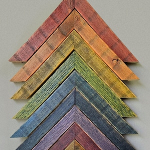 May include: A set of 10 wooden picture frames in various shades of brown, red, green, blue, purple, and white. The frames are arranged in a pyramid shape, with the largest frame at the bottom and the smallest frame at the top.