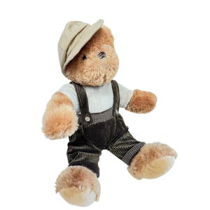 May include: A plush teddy bear wearing a tan newsboy cap, a white sweater, and brown corduroy overalls. The bear has a light brown fur and is posed with its legs extended. A charming stuffed animal.