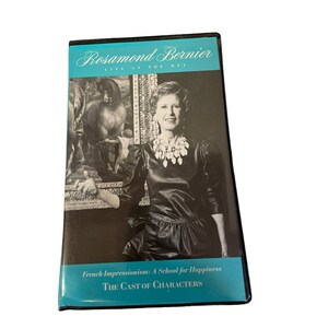Może przedstawiać: Pudełko DVD z napisem "Rosamond Bernier LIVE AT THE MET" w białym tekście na turkusowym tle. Na pudełku znajduje się również tekst "French Impressionism: A School for Happiness" i "THE CAST OF CHARACTERS."