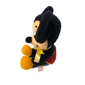 May include: A vintage Mickey Mouse plush toy, featuring black fur, a black nose, and yellow hands and feet. The plush has a yellow bow tie and red shorts. The toy is in a seated position, with a tag attached to the bottom.