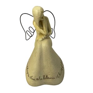May include: A beige angel figurine with black wire wings, seated with a hand to the chin. The base of the figurine has an inscription that reads, "Always to those who believe in the beauty of dreams."