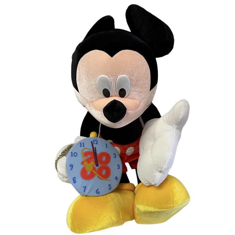 Puede incluir: Un peluche de Mickey Mouse con orejas negras, cara rosa y guantes blancos. Mickey sostiene un reloj azul con el n&uacute;mero 88. La figura lleva pantalones cortos rojos y zapatos amarillos.
