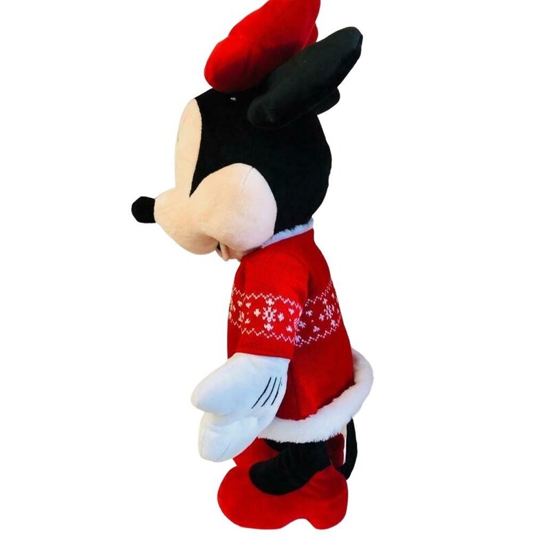 May include: A plush Minnie Mouse doll wearing a red sweater with white snowflake patterns, a matching red bow, and red shoes. The doll has black ears and a white fur trim on the sweater and skirt.