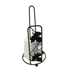 Könnte beinhalten: Schwarzer Toilettenpapierhalter aus Metall mit dekorativem Blättermuster. Der Halter hat eine vertikale Stange zum Tragen und eine kreisförmige Basis. Eine Rolle weißes Toilettenpapier befindet sich im Halter.