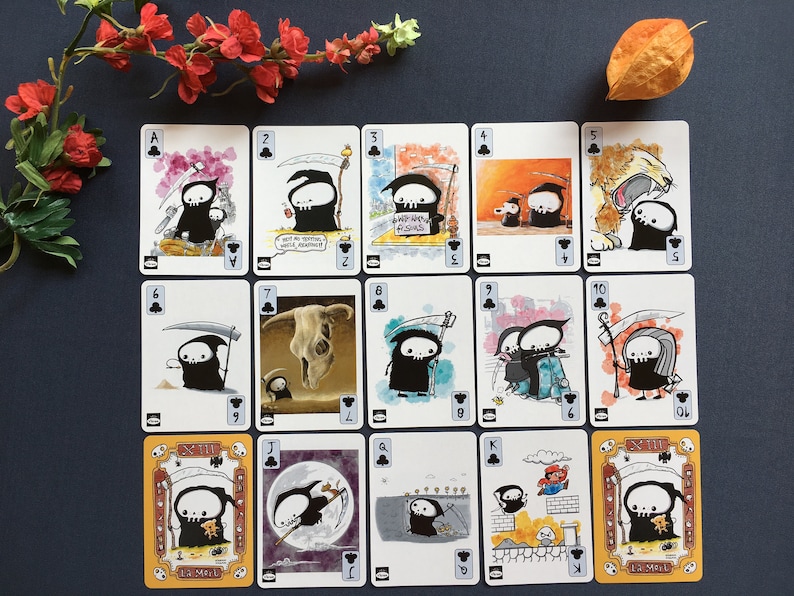 Puede incluir: Una baraja de cartas de juego con una ilustraci&oacute;n en blanco y negro de un esqueleto sosteniendo una guada&ntilde;a. Las cartas est&aacute;n numeradas del 1 al 13 e incluyen el As, el J, la Q y el K. Las cartas est&aacute;n todas en el mismo estilo, con un fondo negro y contornos blancos.