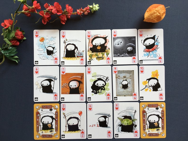 Puede incluir: Una baraja de cartas de juego con una caricatura de la Muerte con una guada&ntilde;a. Las cartas est&aacute;n numeradas del 1 al 10, J, Q, K y A. Las cartas son del palo de corazones.