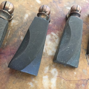 May include: Four black cabinet knobs with a rounded, slightly curved design and a copper colored ball on top.