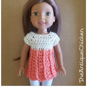 May include: A crocheted doll dress with a white top and coral bottom. The dress has short sleeves and a round neckline.