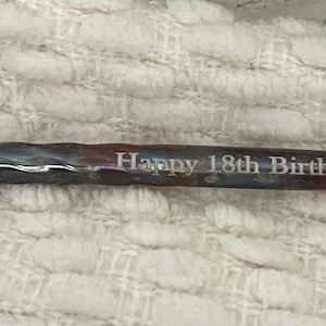 May include: A silver metal rod with a twisted design and the inscription "Happy 18th Birthday Dylan".