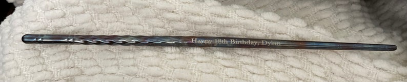 May include: A silver metal rod with a twisted design and the inscription "Happy 18th Birthday Dylan".