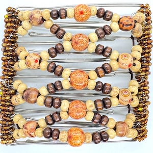 May include: A decorative hair accessory featuring a metal frame adorned with wooden beads in shades of brown, beige, and orange. The beads are arranged in a symmetrical pattern, creating a unique and stylish hair clip. The clip is approximately 10 cm wide.