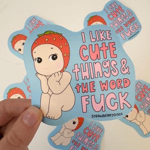 May include: A light blue sticker featuring a cartoon baby wearing a strawberry hat. The sticker has the text "I LIKE CUTE THINGS & THE WORD FUCK" in pink. Several stickers are visible.