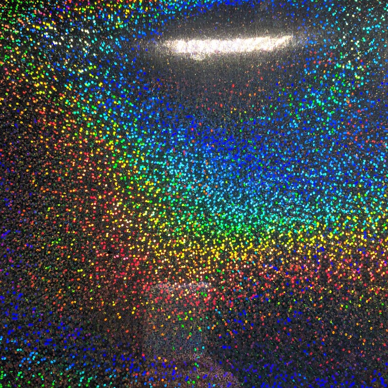 May include: A close-up of iridescent glitter paper with a rainbow effect. The glitter is a mix of silver, gold, red, orange, yellow, green, blue, and purple.