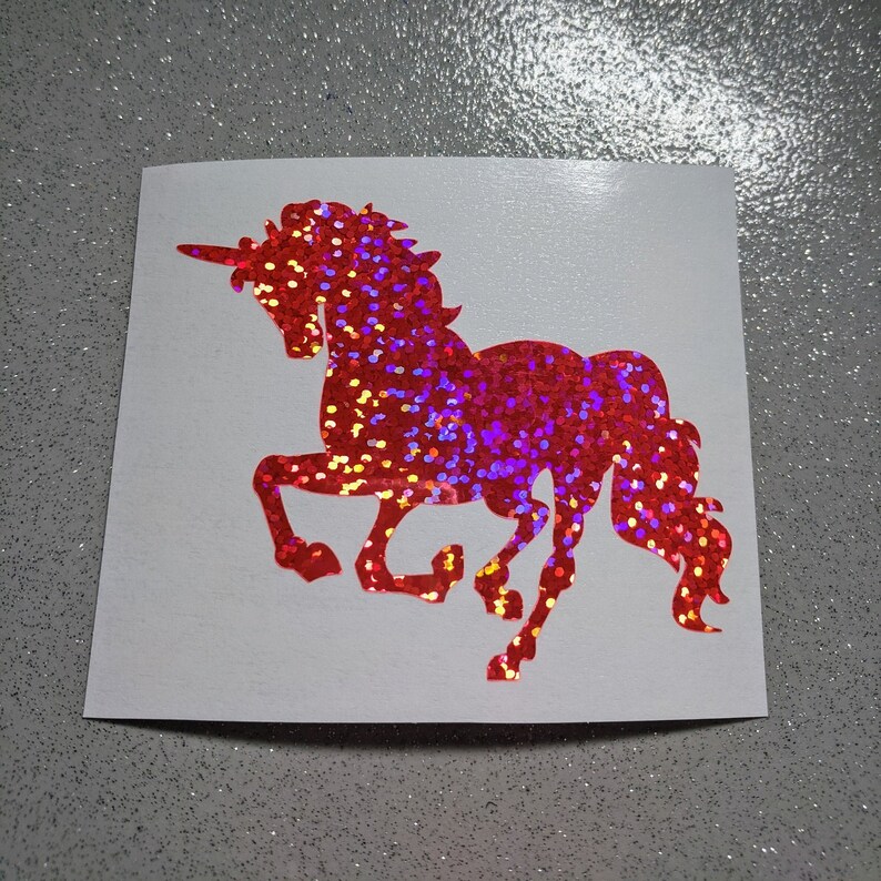 May include: Red glitter unicorn silhouette decal. The unicorn is facing right and has a horn, mane, and tail.