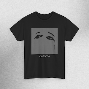 May include: Black t-shirt featuring a square graphic of pixelated eyes with a tear, and the band name "deftones" in white font below. The design is centered on the front of the shirt, which has short sleeves and a crew neck.