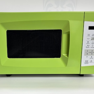 Può includere: Un forno a microonde verde brillante con un display digitale e un pannello di controllo con pulsanti per diverse funzioni. Il forno a microonde ha una porta nera con una finestra a rete.