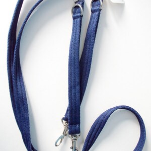 May include: A blue double dog leash with two metal clips. The leash is made of a woven fabric and has a Rex Eze brand tag.