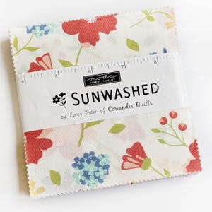 Può includere: Un mucchio di quadrati di tessuto con un motivo floreale in rosso, blu e verde su sfondo bianco. Il tessuto è etichettato "SUNWASHED" di Corey Yoder di Coriander Quilts. Un righello è posto sui quadrati di tessuto.