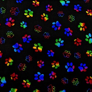 May include: A black fabric featuring a repeating pattern of small, iridescent paw prints. The paw prints display a vibrant spectrum of colors, including blue, green, yellow, orange, and red, creating a reflective, rainbow-like effect across the surface.