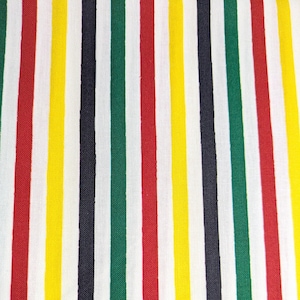 May include: A close-up of a fabric featuring vertical stripes in red, yellow, green, navy, and white. The stripes are evenly spaced and run the length of the material. The fabric appears to be a medium weight cotton or linen.