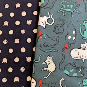 Może przedstawiać: Dwie próbki materiału. Jedna jest granatowa z białymi kropkami i kocimi pyszczkami. Druga jest turkusowa z białymi i turkusowymi ilustracjami kotów, niektóre z czerwonymi akcentami. Zabawny, fantazyjny design.