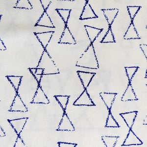 Puede incluir: Tela blanca con un patrón repetitivo de formas de reloj de arena azules. Los relojes de arena están dibujados con un efecto texturizado, similar al de un crayón, creando un diseño simple pero visualmente interesante. La tela tiene una textura sutil y tejida.