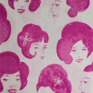 Może przedstawiać: Biała tkanina z powtarzającym się wzorem różowych twarzy kobiet w stylu retro. Twarze mają różne fryzury i wyrazy twarzy, niektóre z kwiatowymi akcentami. Obecna jest również pojedyncza wiśnia.