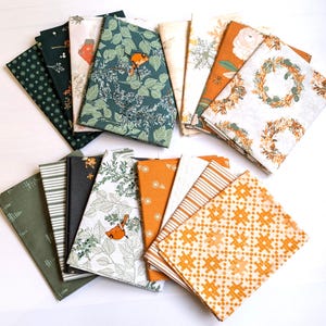 May include: A selection of folded fabric napkins with diverse patterns. Designs include floral, leaf, and geometric prints in shades of green, orange, white, and black. Some napkins feature illustrations of birds and wreaths.