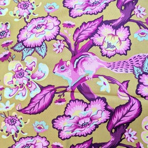 Può includere: Uno scoiattolo rosa e viola è seduto su un ramo di un albero con fiori rosa e viola. Lo sfondo è di colore giallo senape.