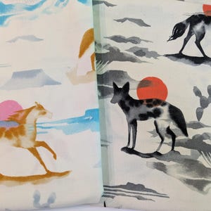 Puede incluir: Tela con un diseño de acuarela con caballos, coyotes, cactus y un sol poniente. La paleta de colores incluye tonos de naranja, rosa, azul y gris sobre un fondo crema. La tela tiene un tema desértico.