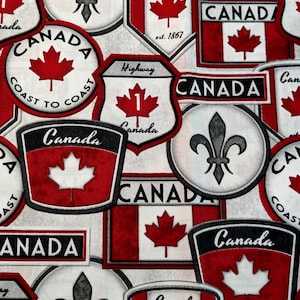 May include: A white fabric featuring a repeating pattern of Canadian-themed emblems, including red maple leaves, black fleur-de-lis symbols, and shield-shaped patches with the text Canada, Highway 1, and Coast to Coast printed in black and red.