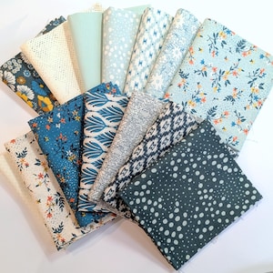 Może przedstawiać: Kolekcja różnych próbek tkanin w różnych wzorach i kolorach. Tkaniny obejmują wzory kwiatowe, geometryczne i w kropki w odcieniach niebieskiego, białego i kremowego. Niektóre tkaniny mają teksturowany, otwarty splot.