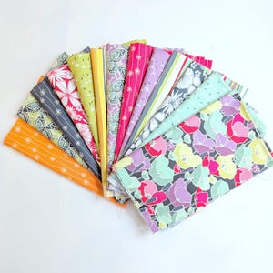 以下が含まれることがあります： 白い背景に扇状に広げられた、カラフルな生地の見本コレクション。オレンジ、ピンク、グリーン、ブルーの色合いで、さまざまな花柄、蝶柄、ストライプ柄が特徴です。生地はおそらく綿または同様の素材です。