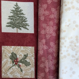 May include: Close-up of festive fabric rolls. The fabrics display a deep red background with Christmas tree and holly prints. Other fabrics include a snowflake pattern and a cream-colored fabric with gold snowflakes.