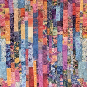 May include: A vibrant patchwork quilt featuring vertical strips of patterned fabric in shades of blue, purple, orange, and pink. The quilt's surface has a textured feel, with visible stitching throughout.